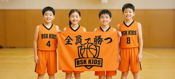 上下オレンジ色のバスケットボールのユニフォームを着た4人の子供が、バスケチームロゴと「全員で勝つ」という文言が黒色で名入れ印刷された、オレンジのオリジナル応援旗を手で持っているイメージ画像