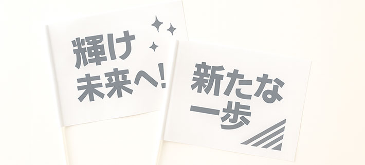「輝け未来へ！」と名入れ印刷された、白色の応援旗と「新たな一歩」と名入れ印刷された白色の応援旗のイメージ画像