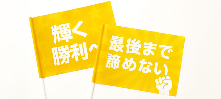 白い文字で「輝く勝利へ」と名入れ印刷された、黄色のオリジナル応援旗と、白い文字で「最後まで諦めない」と名入れ印刷された黄色のオリジナル応援旗のイメージ画像